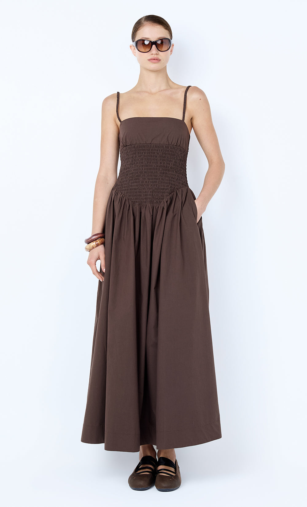 Woman wearing a brown dress with sunglasses on a white background