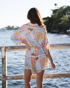Woman wearing a colorful patterned dress standing by a waterfront.