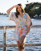 Woman in a colorful dress standing by a waterfront with a scenic background