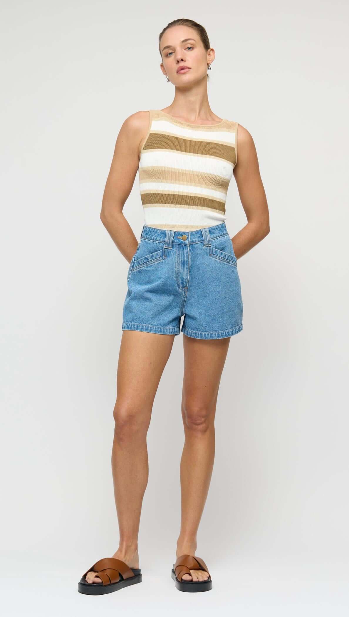 Woman wearing a striped top and denim shorts on a white background