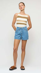 Woman wearing a striped top and denim shorts on a white background