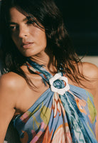 Woman wearing a colorful halter top with a white flower accessory.