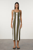Woman wearing a green and white striped dress against a plain background