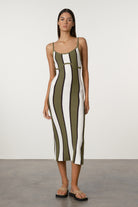 Woman wearing a green and white striped dress against a plain background