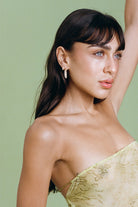 Woman wearing a strapless green dress against a light green background