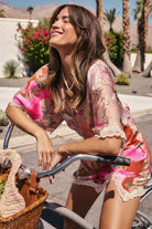 Rocky Barnes in a colorful outfit riding a bike with a basket in a sunny outdoor setting.