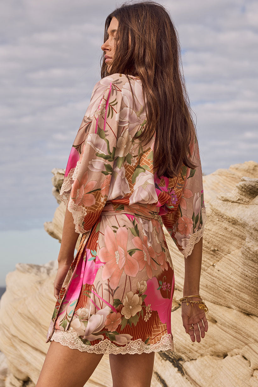 Woman wearing a floral dress standing on rocky cliffs with ocean view