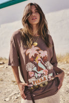 Rocky Barnes wearing a brown t-shirt with a colorful graphic design in an outdoor setting.
