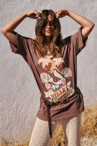 Rocky Barnes wearing a brown t-shirt with a graphic design against a textured wall.