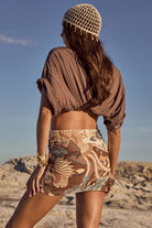 Woman in desert wearing a patterned outfit and hat against a clear blue sky.