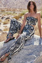 Woman in a floral outfit sitting on a rock in a desert setting