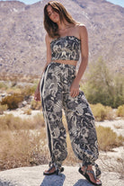 Woman in a black and white floral outfit standing in a desert landscape