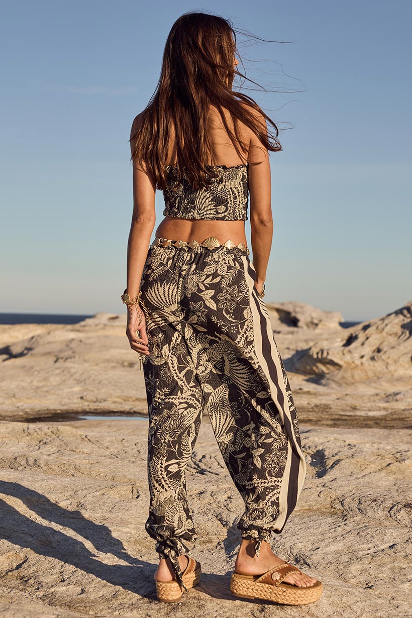 Woman in patterned outfit standing on a rocky beach