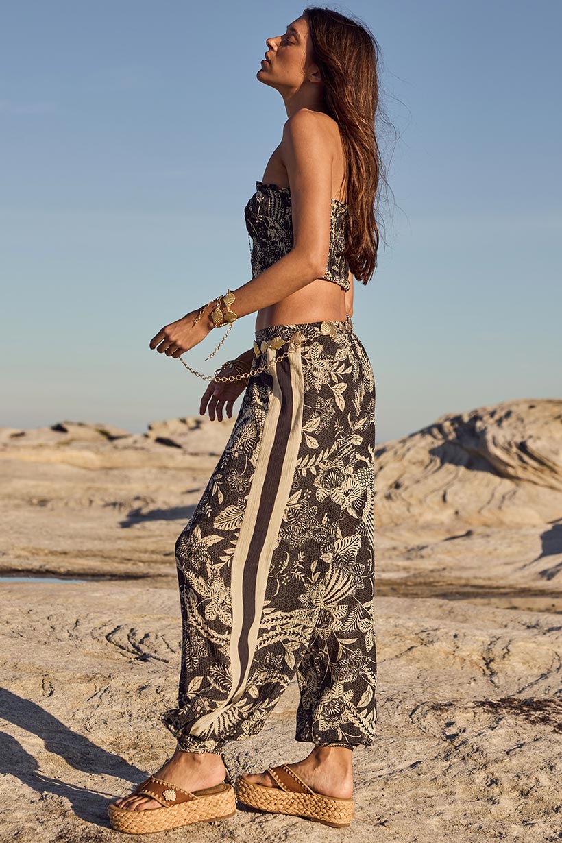 Woman in a patterned outfit standing on rocky terrain with a clear sky.