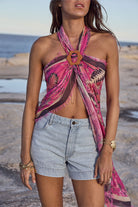 Rocky Barnes on a beach wearing a pink patterned top and denim shorts.