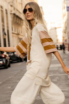 Woman in a stylish outfit with a striped shirt and beige pants walking on a city street.