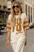 Woman wearing a white and brown striped shirt with a number on a city street.