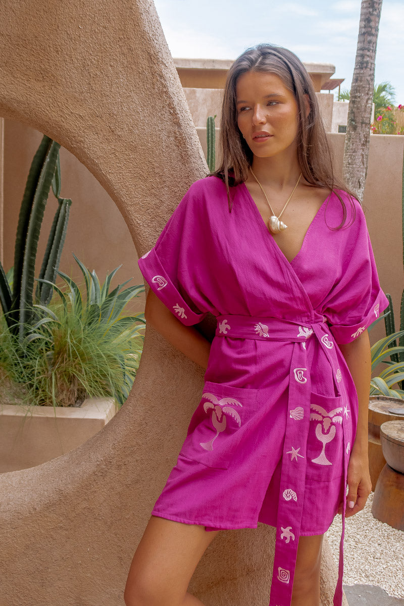 Woman wearing a pink robe with white patterns in an outdoor setting.