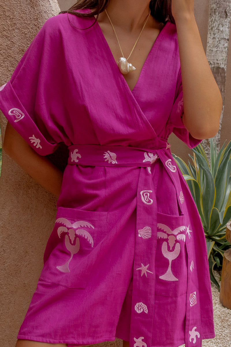 Person wearing a pink dress with white patterns against a neutral background