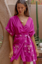 Woman wearing a pink dress with patterns in an outdoor setting