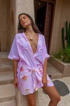 Woman wearing a pink robe with floral patterns standing outdoors.