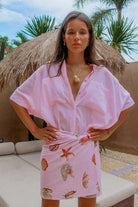Woman wearing a pink cover-up with a shell pattern in a tropical setting