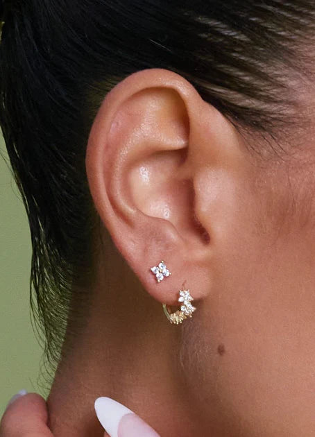 Close-up of an ear wearing gold earrings with a blurred background