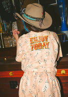 Person wearing a dress with 'ENJOY TODAY' text in a bar setting