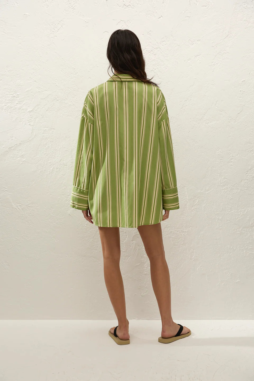 Person wearing a green and white striped shirt against a white background