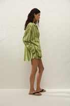 Woman wearing a green striped shirt and shorts against a white background