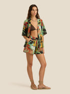 Woman wearing a colorful kimono-style jacket and shorts on a beige background