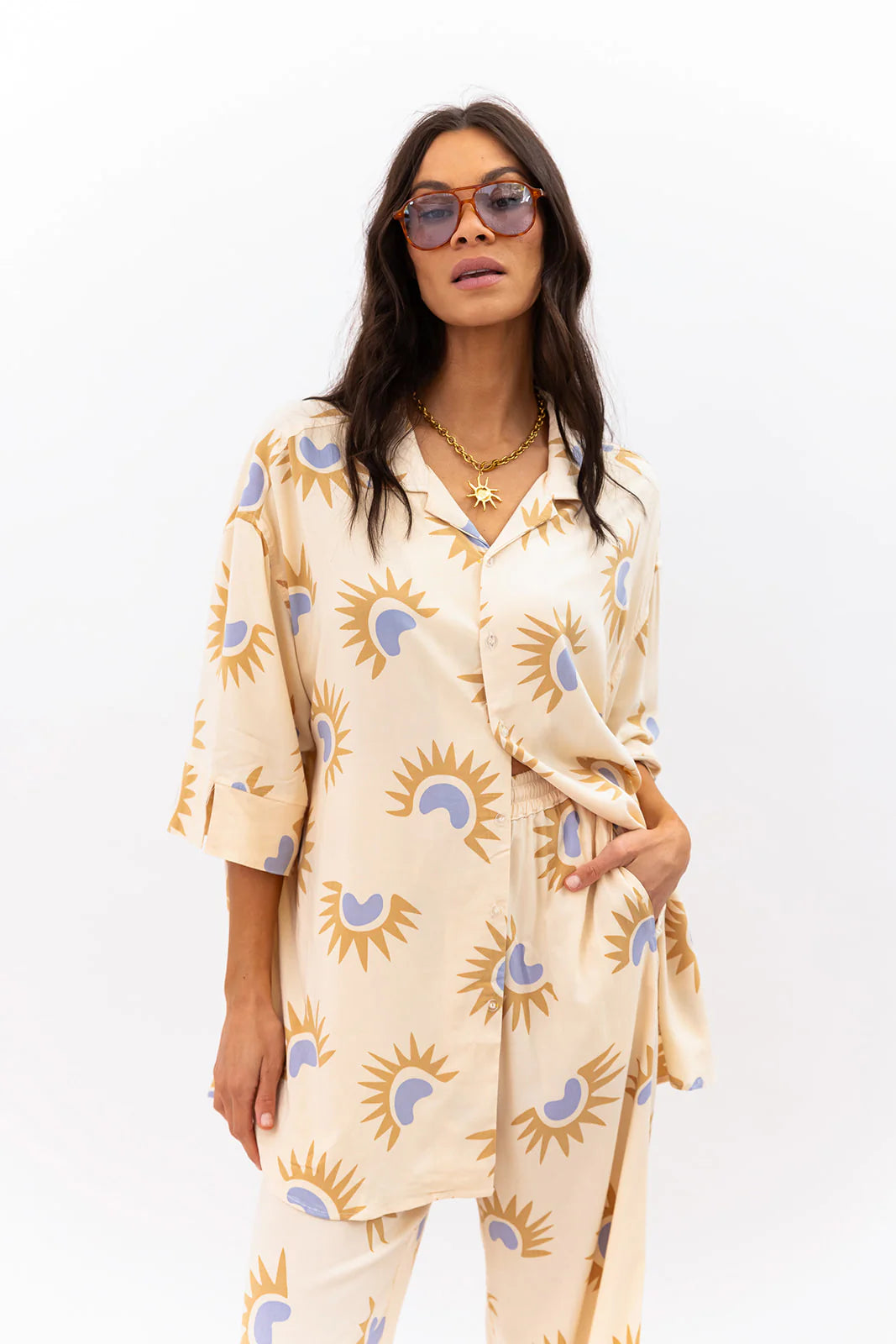 Woman wearing a cream-colored outfit with sun pattern on a white background