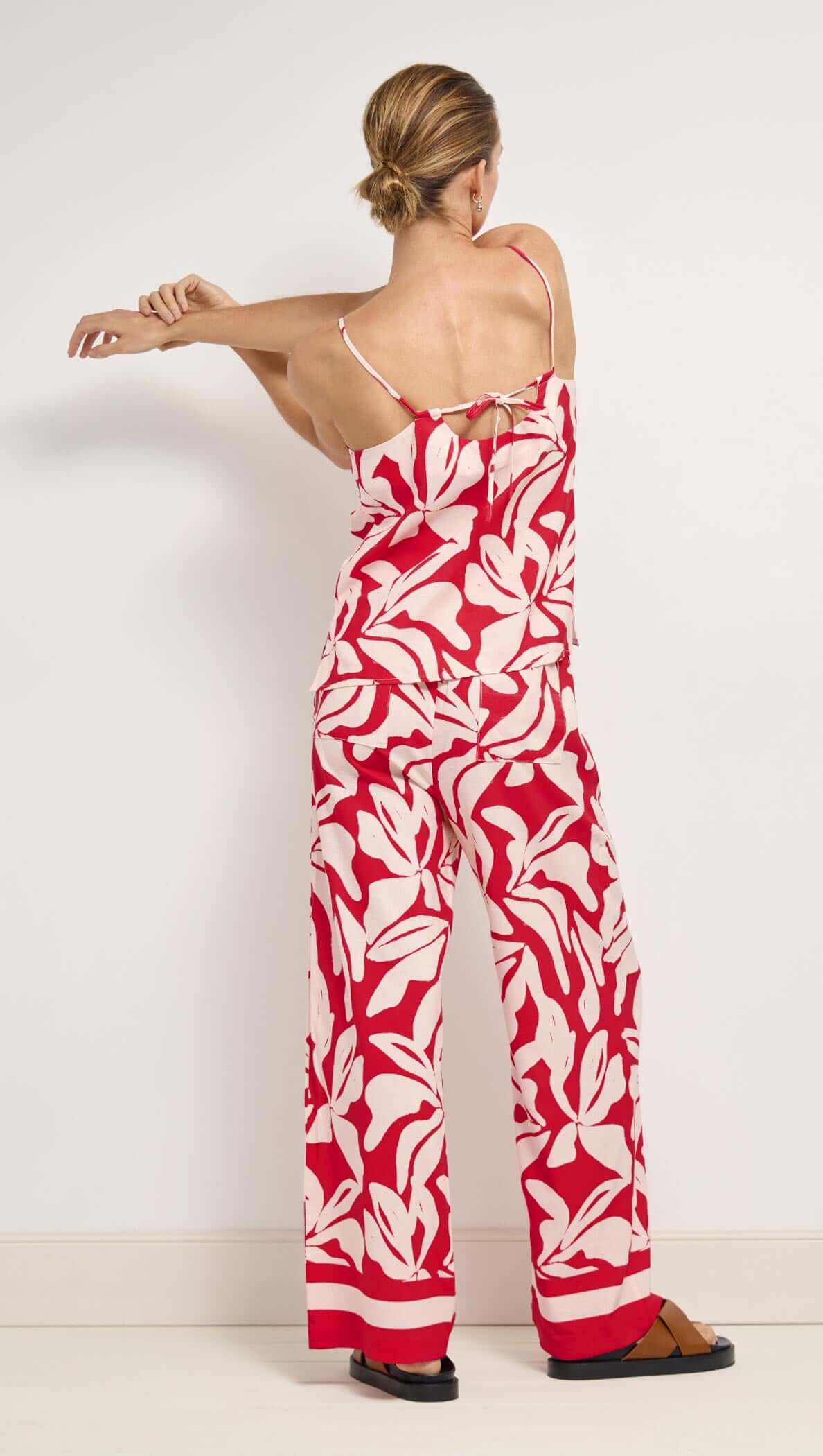 Woman wearing a red and white floral jumpsuit against a white background