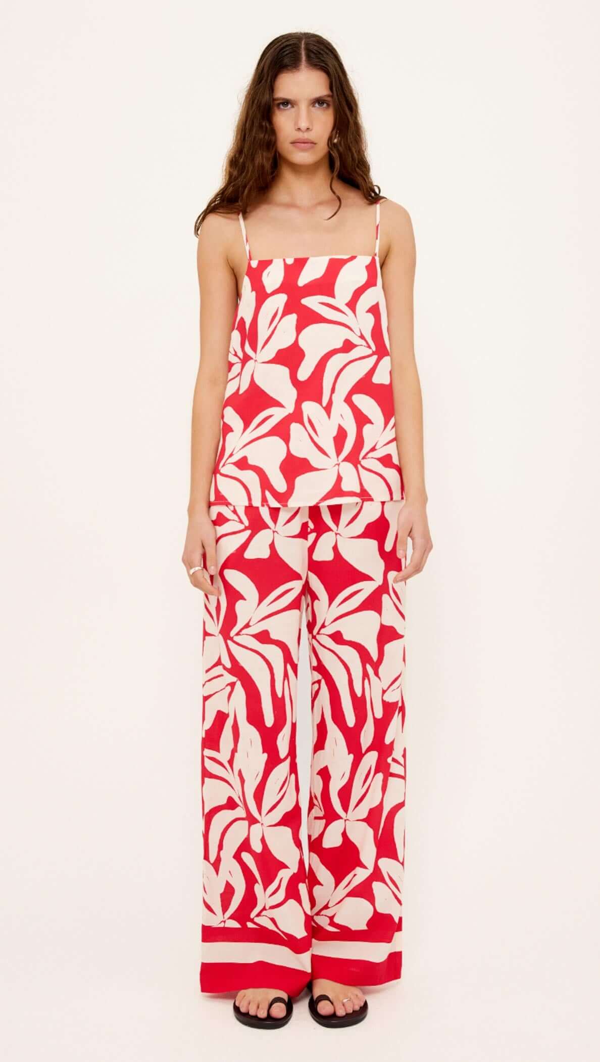 Woman wearing a red and white floral jumpsuit on a white background