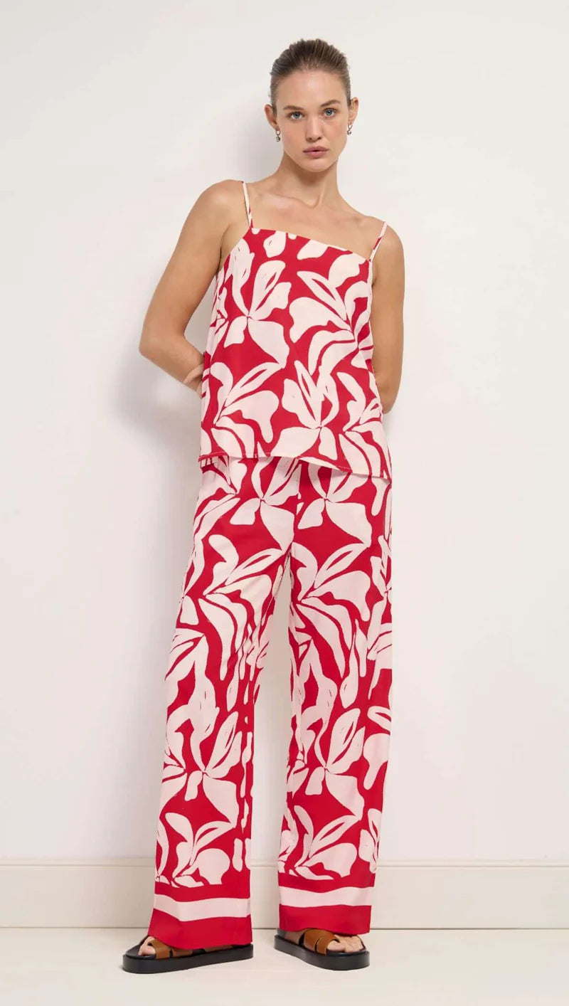 Woman wearing a red and white floral jumpsuit against a white background