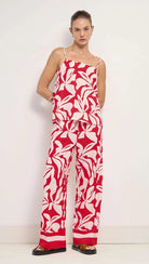 Woman wearing a red and white floral jumpsuit against a white background