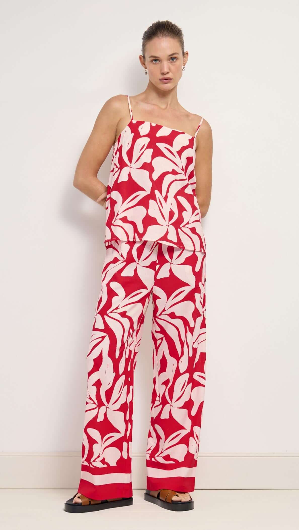 Woman wearing a red and white floral jumpsuit against a white background