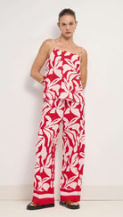 Woman wearing a red and white floral jumpsuit against a white background