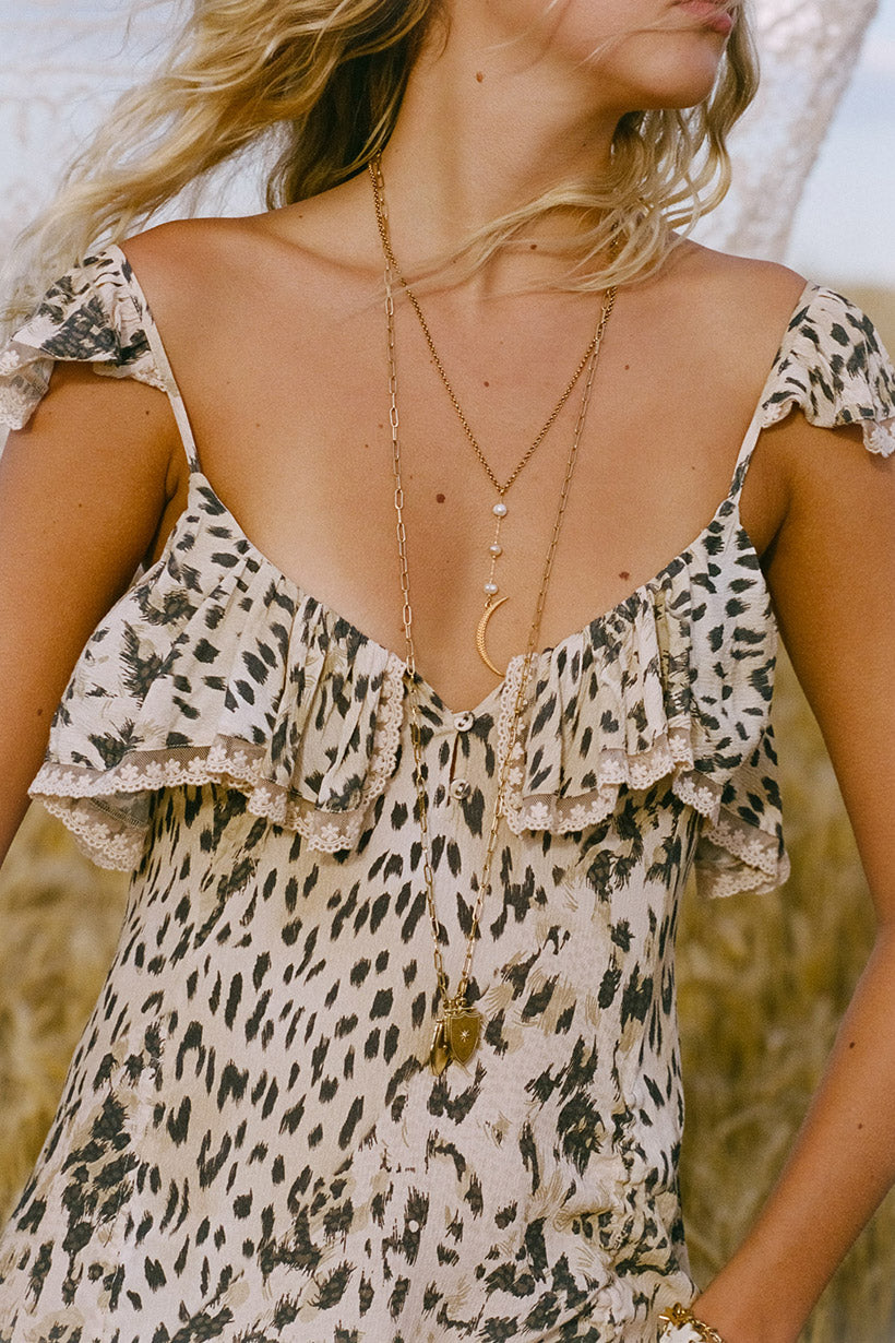 Woman wearing a leopard print dress with a deep neckline and layered necklaces.