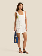 Woman wearing a white dress with floral patterns on a beige background