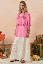 Woman wearing a pink 'Marina Piccola' shirt with a rustic background