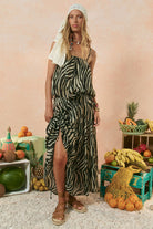 Woman in a zebra print dress standing in front of a fruit display with a pink background