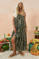 Woman in a zebra print dress standing in front of a display of fruits and vegetables.