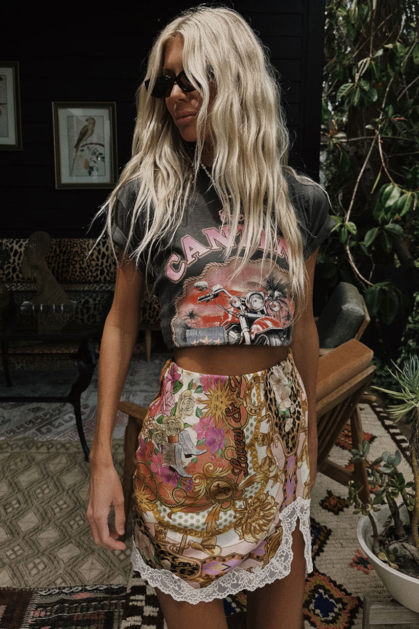 Woman wearing a graphic t-shirt and patterned skirt in an indoor setting