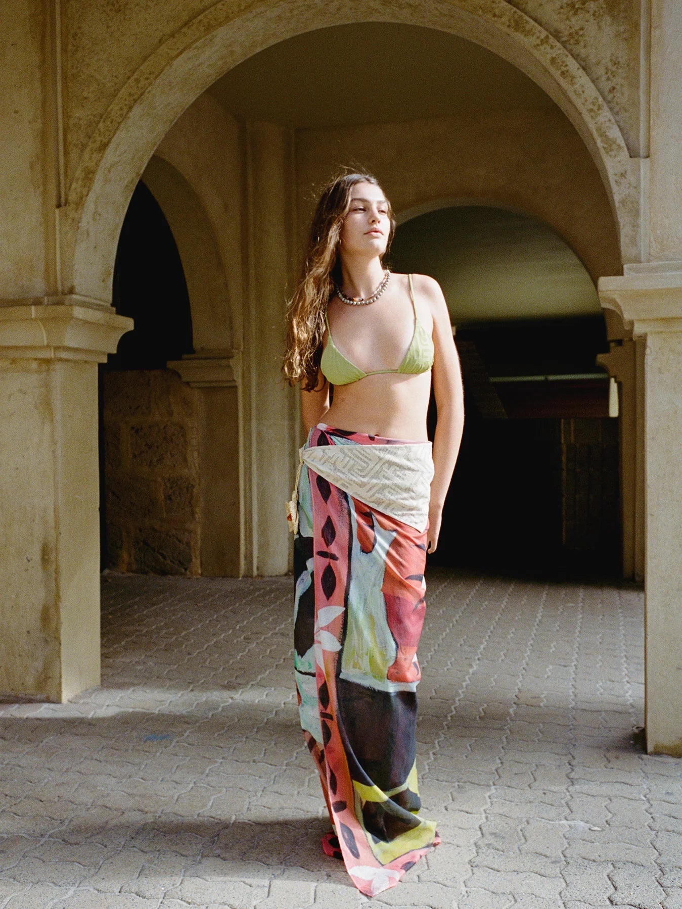 Woman in a colorful dress standing under an archway