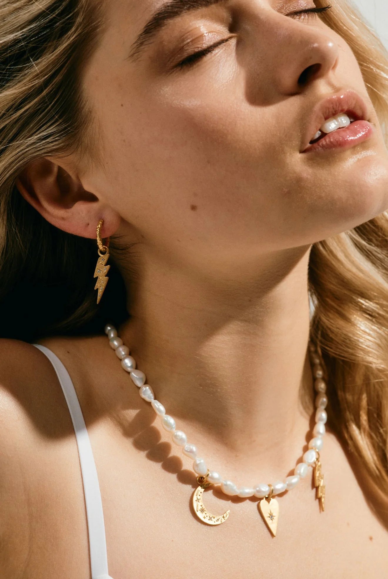 Woman wearing a pearl necklace and gold earrings with a blurred background