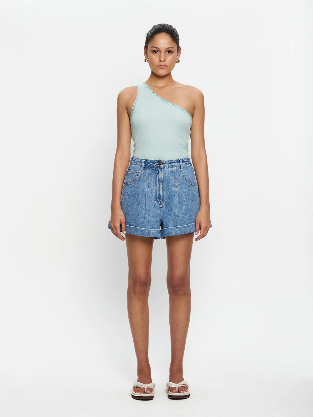 Woman wearing mint one shoulder tank and denim shorts