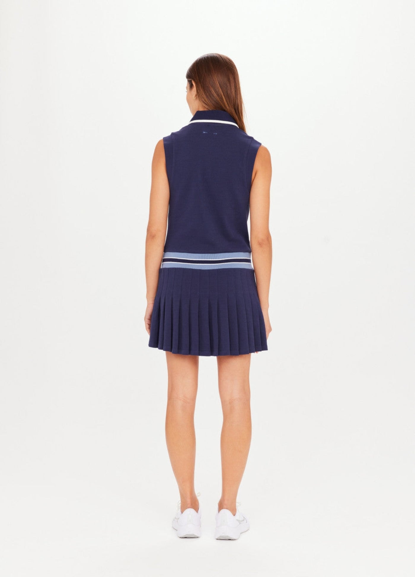 Navy blue tennis dress with button through and stand collar featuring a pleated skirt