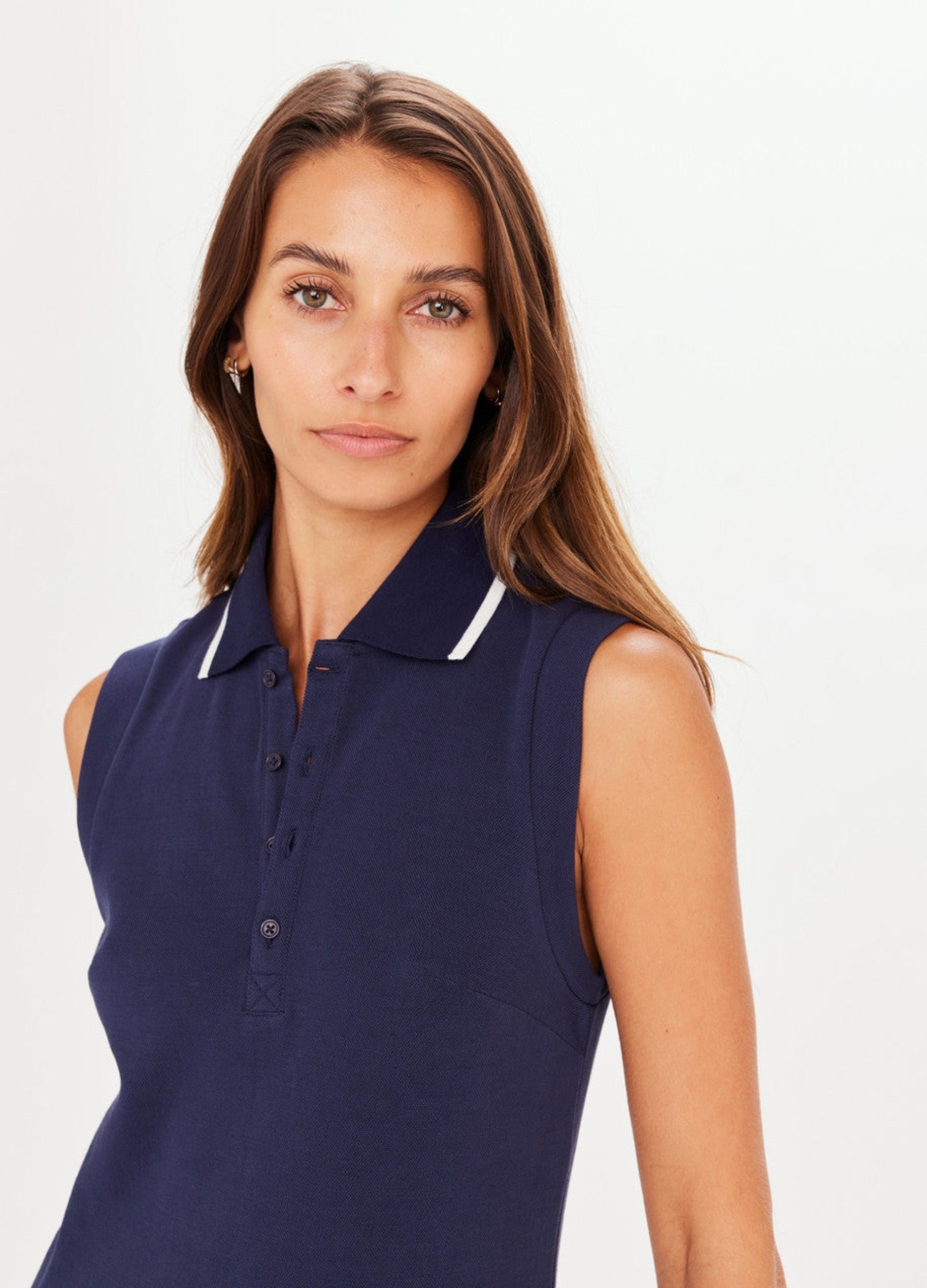 Navy blue tennis dress with button through and stand collar featuring a pleated skirt