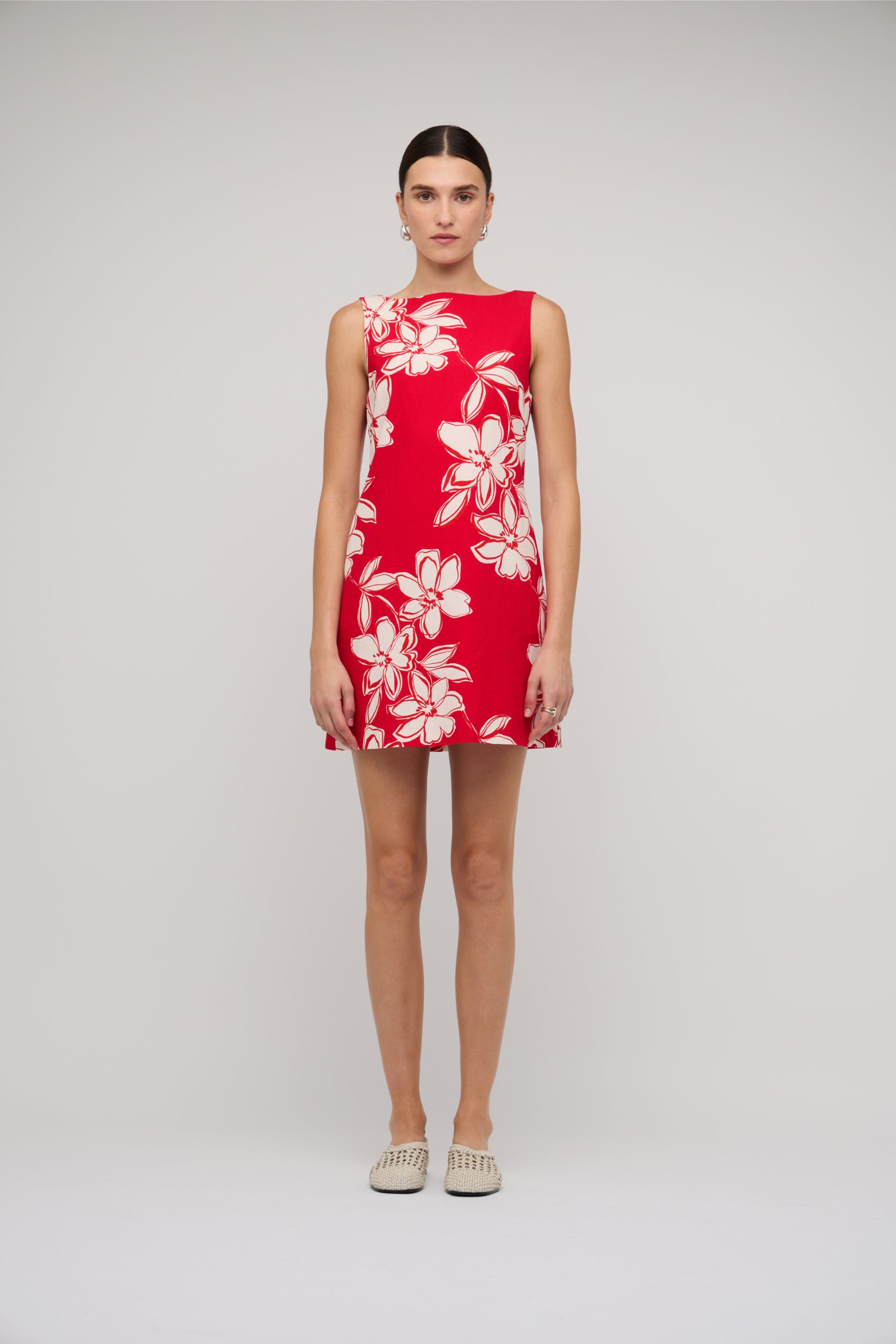 Red dress with white floral pattern worn by a model on a plain background